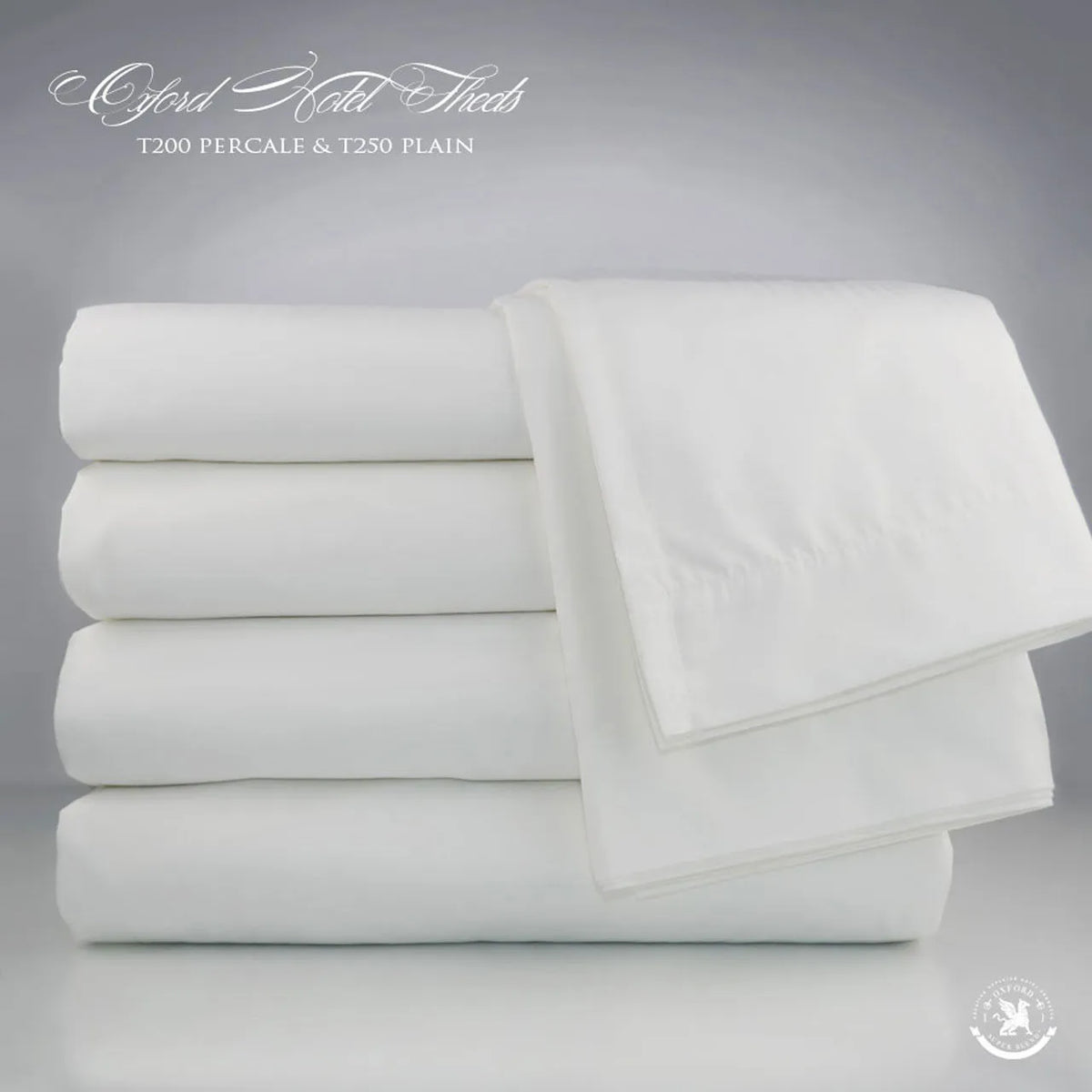 A stack of neatly folded white bed sheets is displayed against a light gray background. The text at the top reads, Ganesh Mills Fitted Sheets - Oxford T250 Satin Bed Linen hotel-quality fitted sheets.