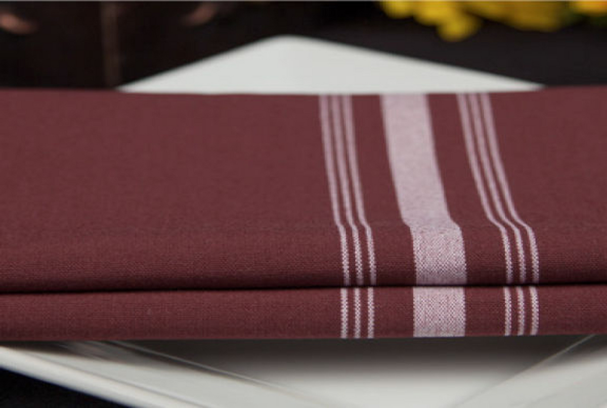 A folded maroon Premier Bistro Napkin by 1Concier with white vertical stripes rests neatly on a white square plate, with a blurred background.