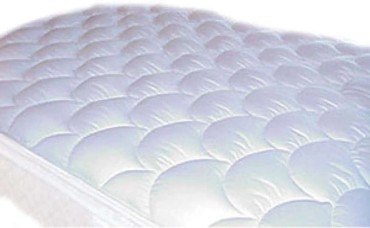 A close-up of Ganesh Mills’ Oxford Quilted Bed Pads Fitted, showing the white, scalloped padded design for a soft surface. Plain, blurred background. Perfect choice for bulk wholesale bedding needs.