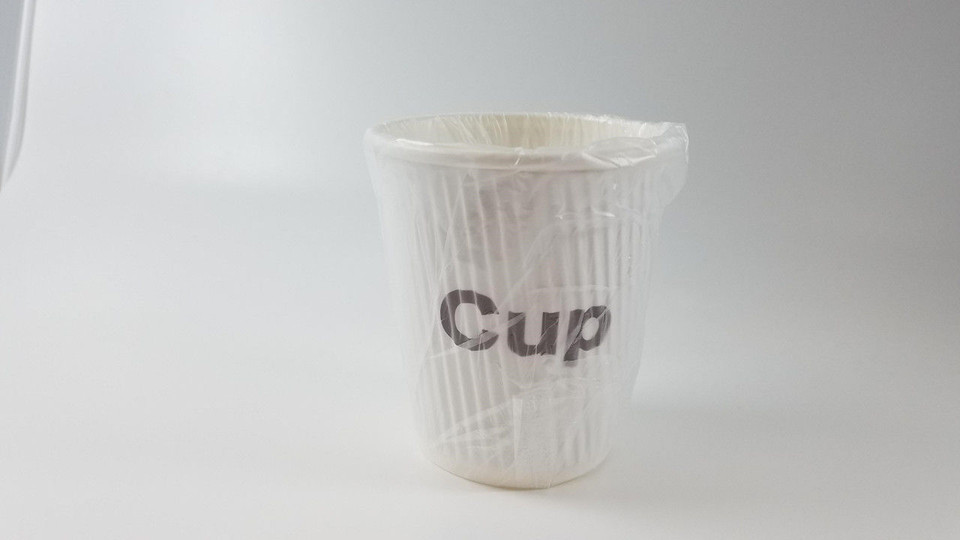 The Ganesh Mills Plastic Lid for 9 oz Coffee Cup Wholesale is perfect for securing coffee cups, maintaining freshness and convenience—ideal for use with white paper cups wrapped in clear plastic on any plain white surface.