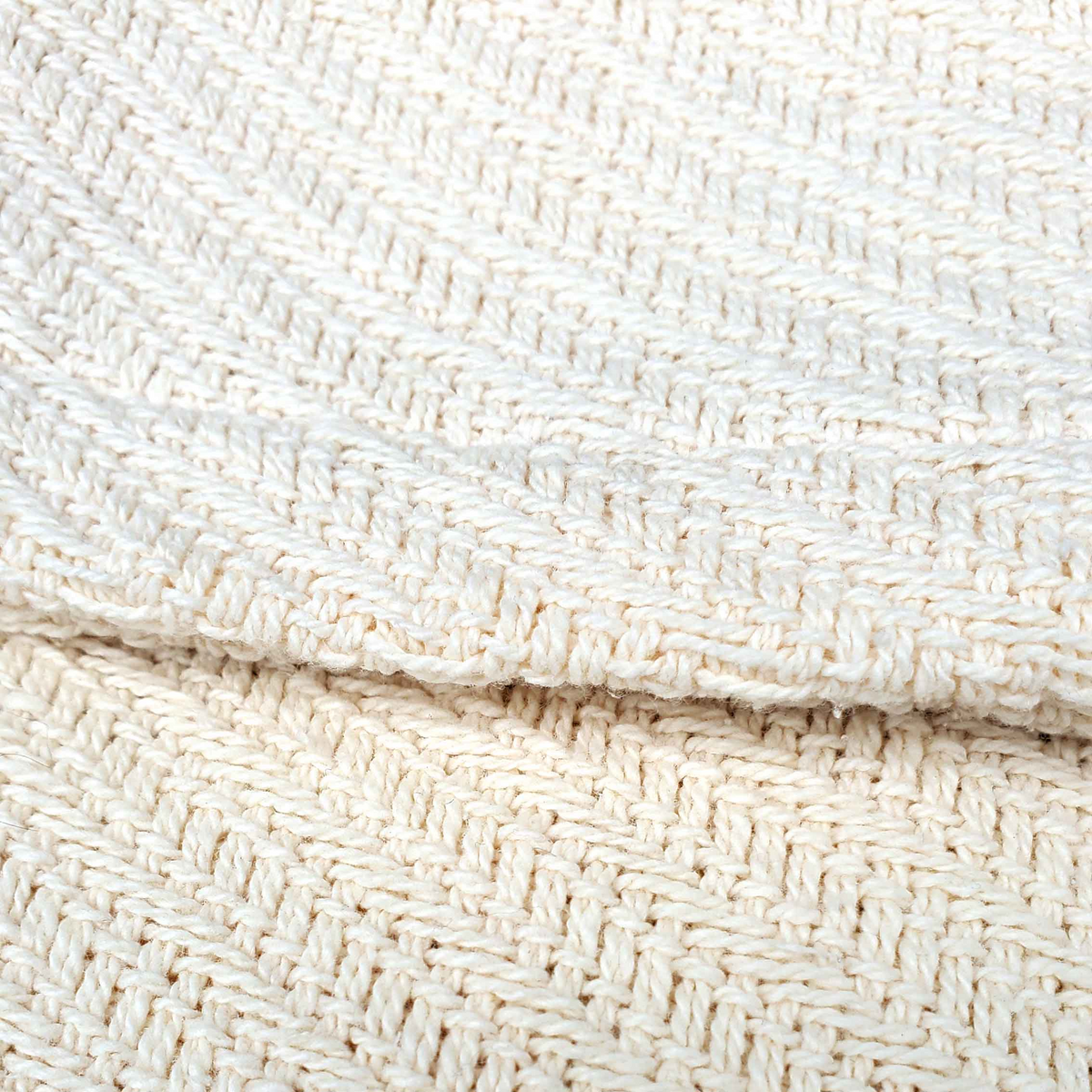 Close-up of the Sovereign - Cotton Blanket by WestPoint Home, featuring cream-colored, textured woven cotton with a chevron pattern, detailed stitching, and a soft, cozy appearance.
