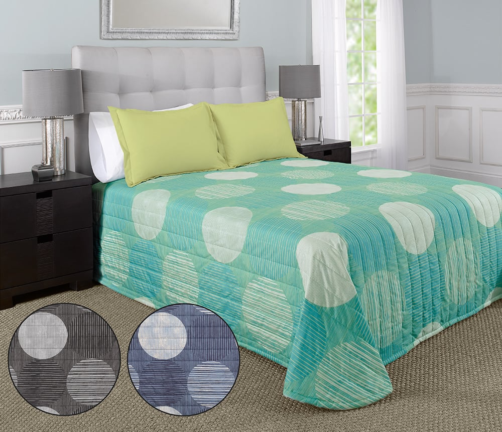 A neatly made bed features WestPoint Homes Bedspreads - Solids, a light gray tufted headboard, green pillows, and a turquoise comforter with circle patterns. This custom EcoPure polyester bedding is paired with modern side tables and lamps. Alternate colors available.