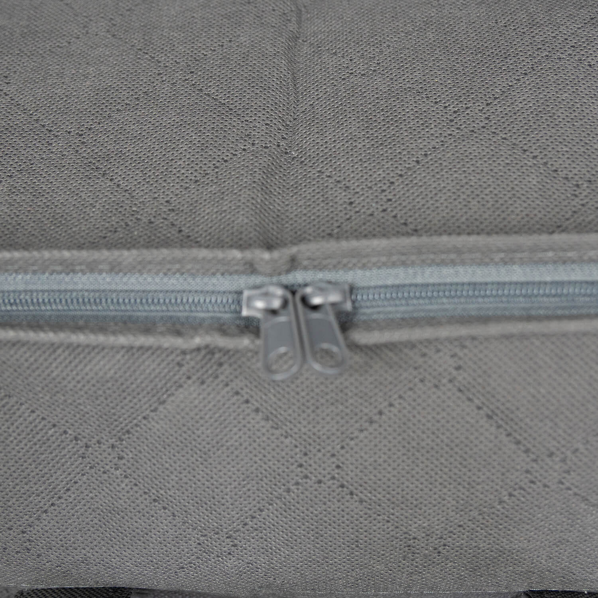 Close-up of the Martex Basics - Closet Storage Bag by WestPoint Home, a gray diamond-quilted pillow bag with a blue zipper and two metal pulls at the center.