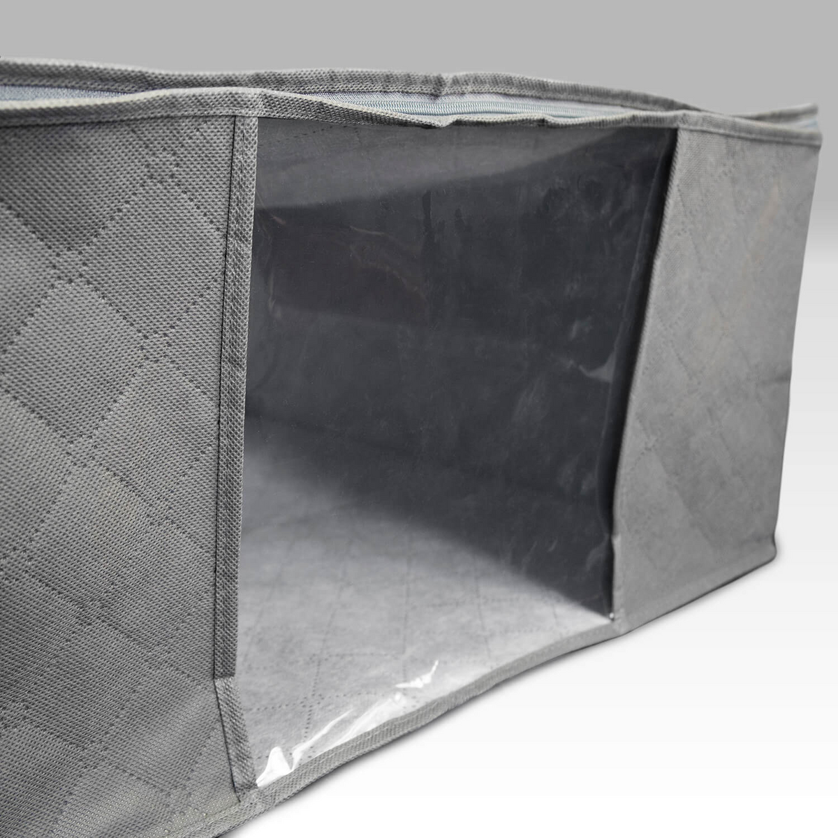 A close-up of the WestPoint Home Martex Basics Closet Storage Bag shows its gray quilted non-woven fabric and clear plastic window displaying the empty interior, set against a light gray gradient background.