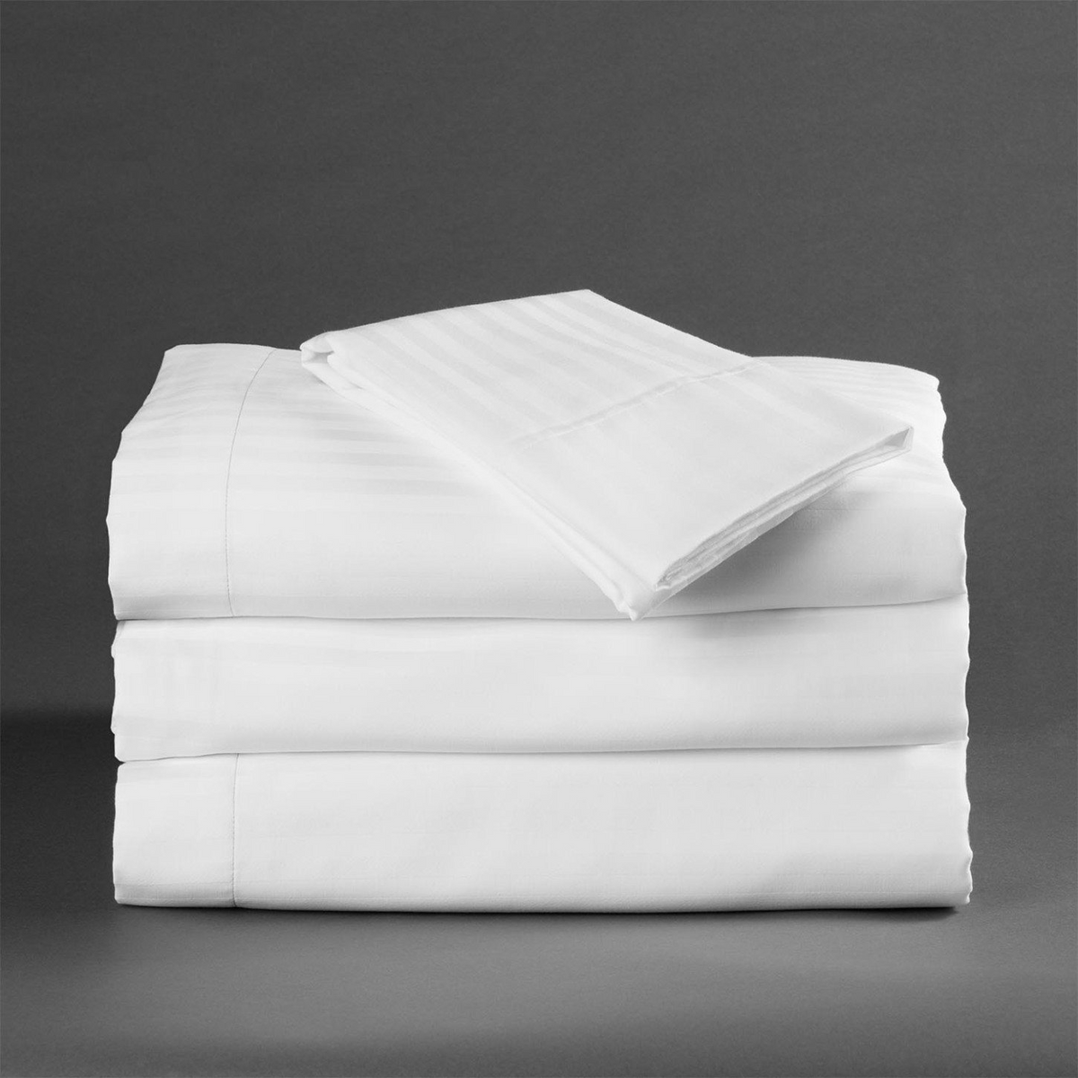 A neatly folded stack of WestPoint Home Martex Millennium 250 Stripe Sheets and Pillow Case set against a plain gray background.
