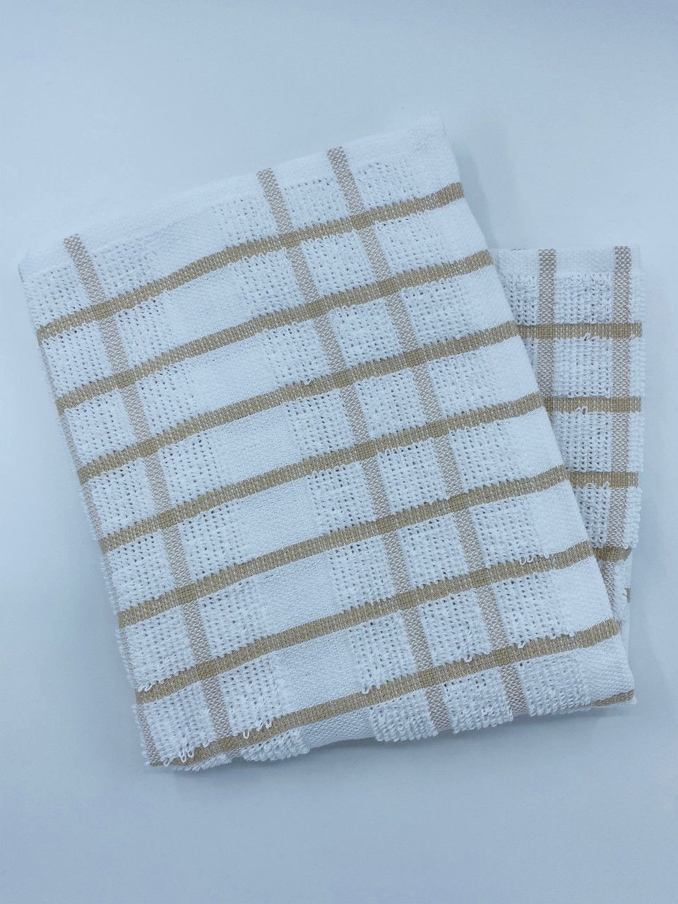 A Ganesh Mills Dish Cloths - Colored/Checkered Pattern Oxford Kitchen Ensemble piece, featuring a beige plaid design on white ringspun cotton, is neatly folded on a plain light background.