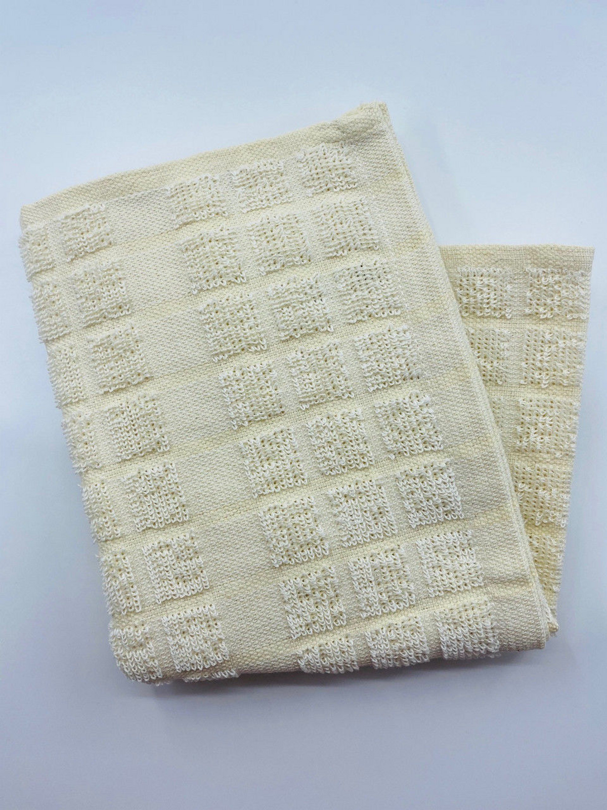 A folded Kitchen Towels - Colored/Checkered Pattern Oxford Kitchen Ensemble by Ganesh Mills is displayed on a plain white surface.