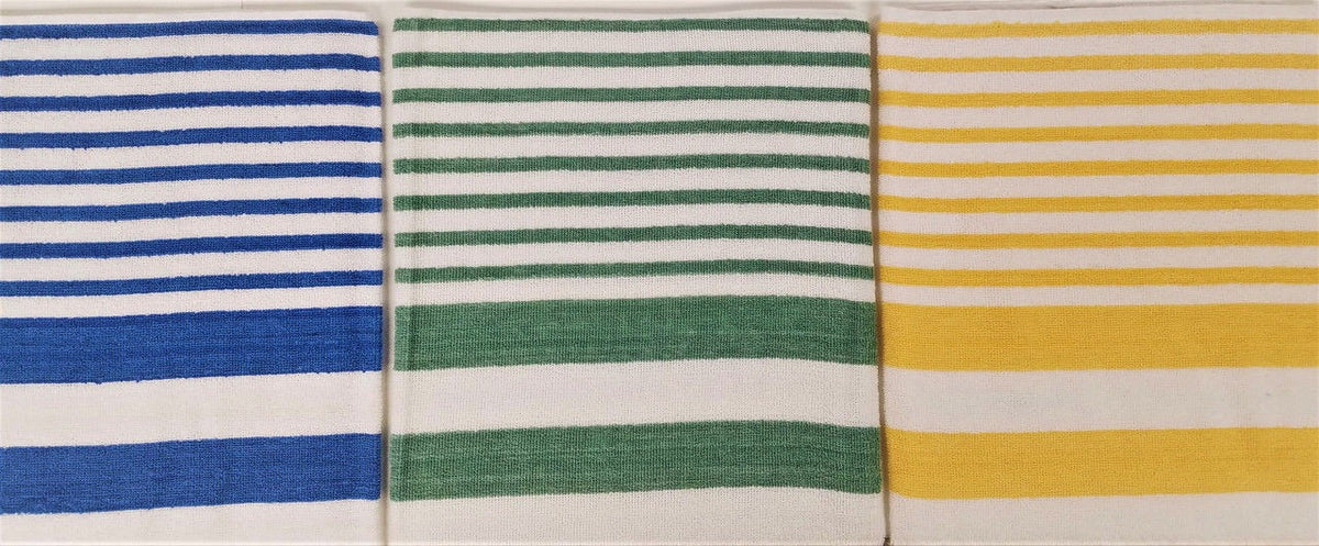 Three Ganesh Mills Tropical Stripe Pool Towels are side by side: one blue and white, one green and white, and one yellow and white. Each features evenly spaced horizontal stripes for a classic cabana look.