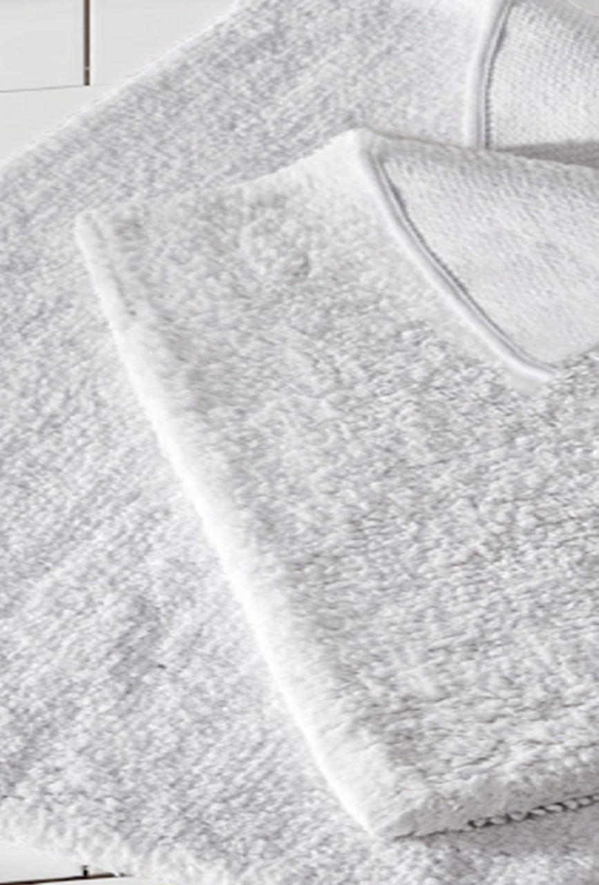 A close-up view of two neatly folded white towels beside the Dream Bath Rug by 1Concier, highlighting their soft texture and the rug’s luxurious appeal.