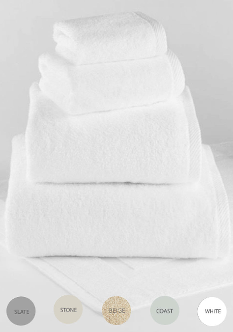 Four neatly folded white Guest Spa-terry traditional towels by 1Concier rest atop a matching towel, with circular swatches below showing available colors: Slate, Stone, Beige, Coast, and White for an elegant touch.