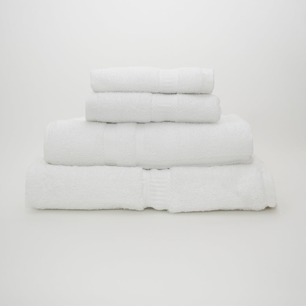 Four neatly folded Avalon Premium Wash Cloths by Calderon Textiles, made from 100% cotton, are stacked in a pyramid shape against a plain white background, highlighting their plush softness and quality.