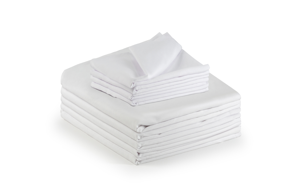 A neatly folded stack of KSE Bath Blankets in unbleached white (86% cotton, 14% poly), with pillowcases on top, evokes the crisp look of hospital bedding against a plain white background.