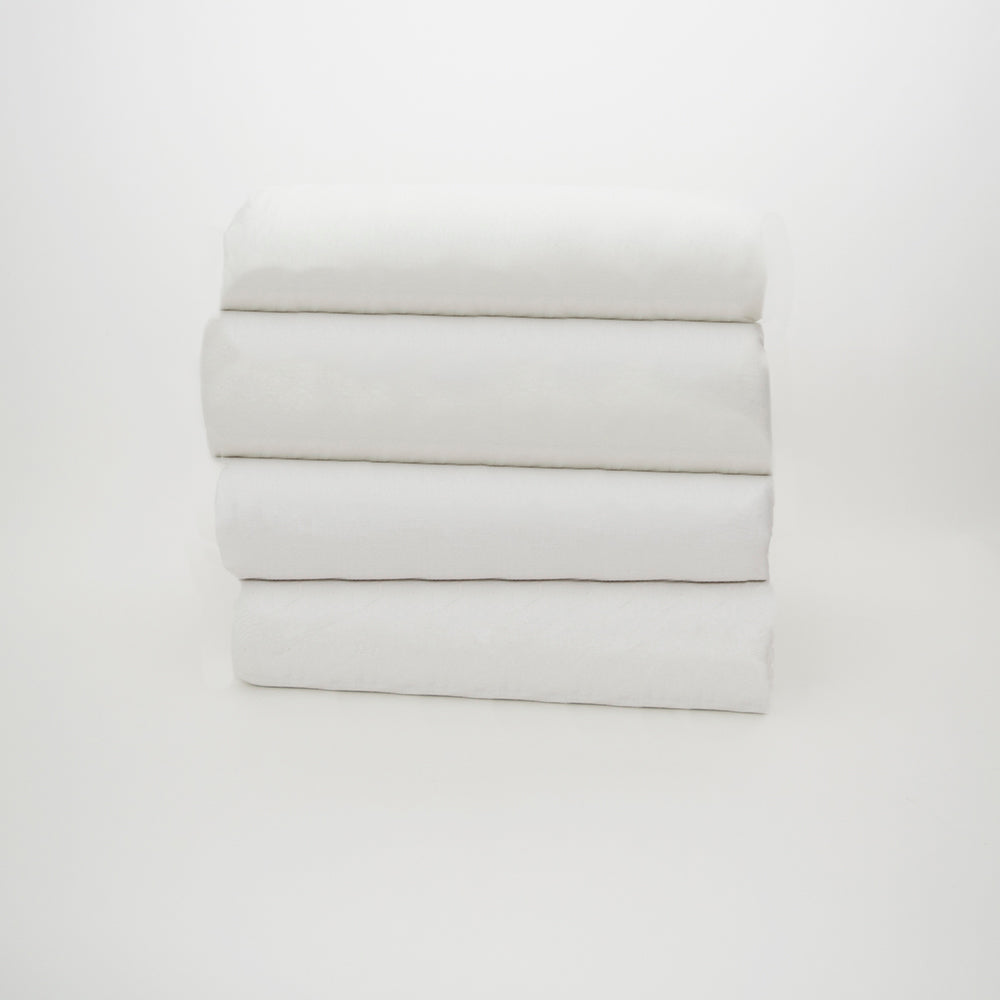 A neatly folded stack of four white towels or sheets, featuring the Calderon Textiles White Knitted fitted with spandex, on a plain white background.