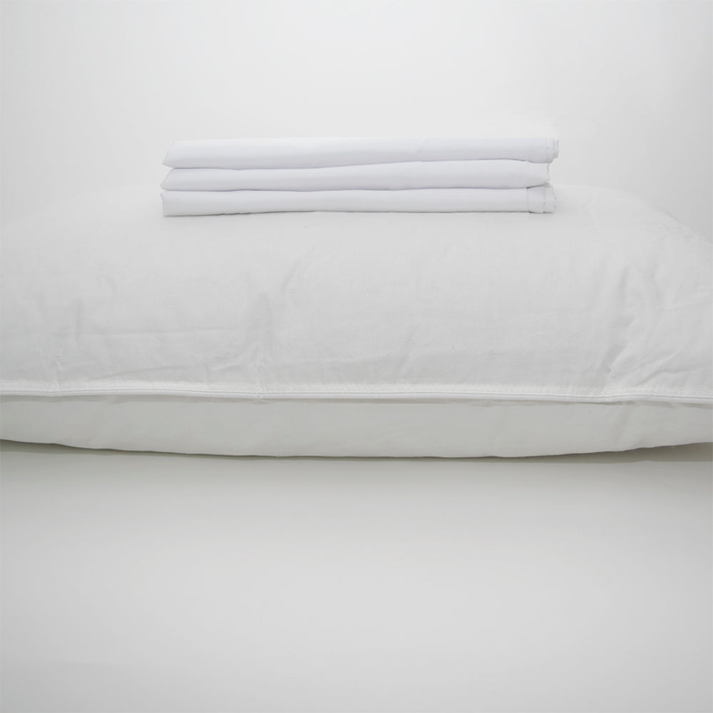 A Calderon Textiles Microfiber Standard Pillowcase – Microtex lies flat on a white surface with a neatly folded set of sheets on top, all set against a plain white background.