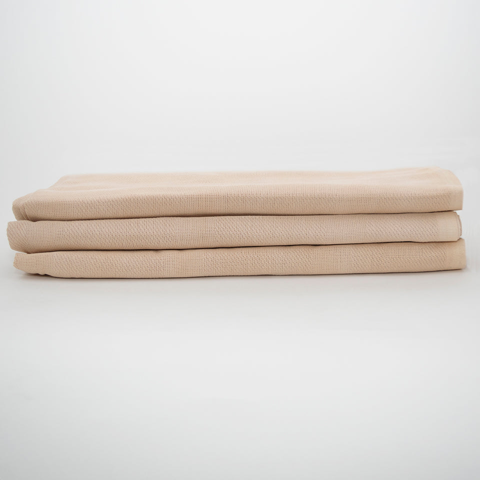 A stack of three neatly folded Calderon Textiles Thermal Blanket Unbleached towels sits on a white surface and background, offering the cozy warmth and comfort of thermal blankets for any space.