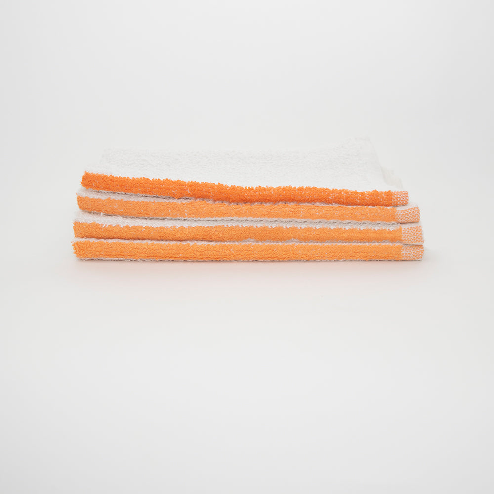 Four Calderon Textiles Bar Mop Dura bar towels, made of white cotton terry with orange trim, are neatly folded and stacked on a white surface against a plain white background.