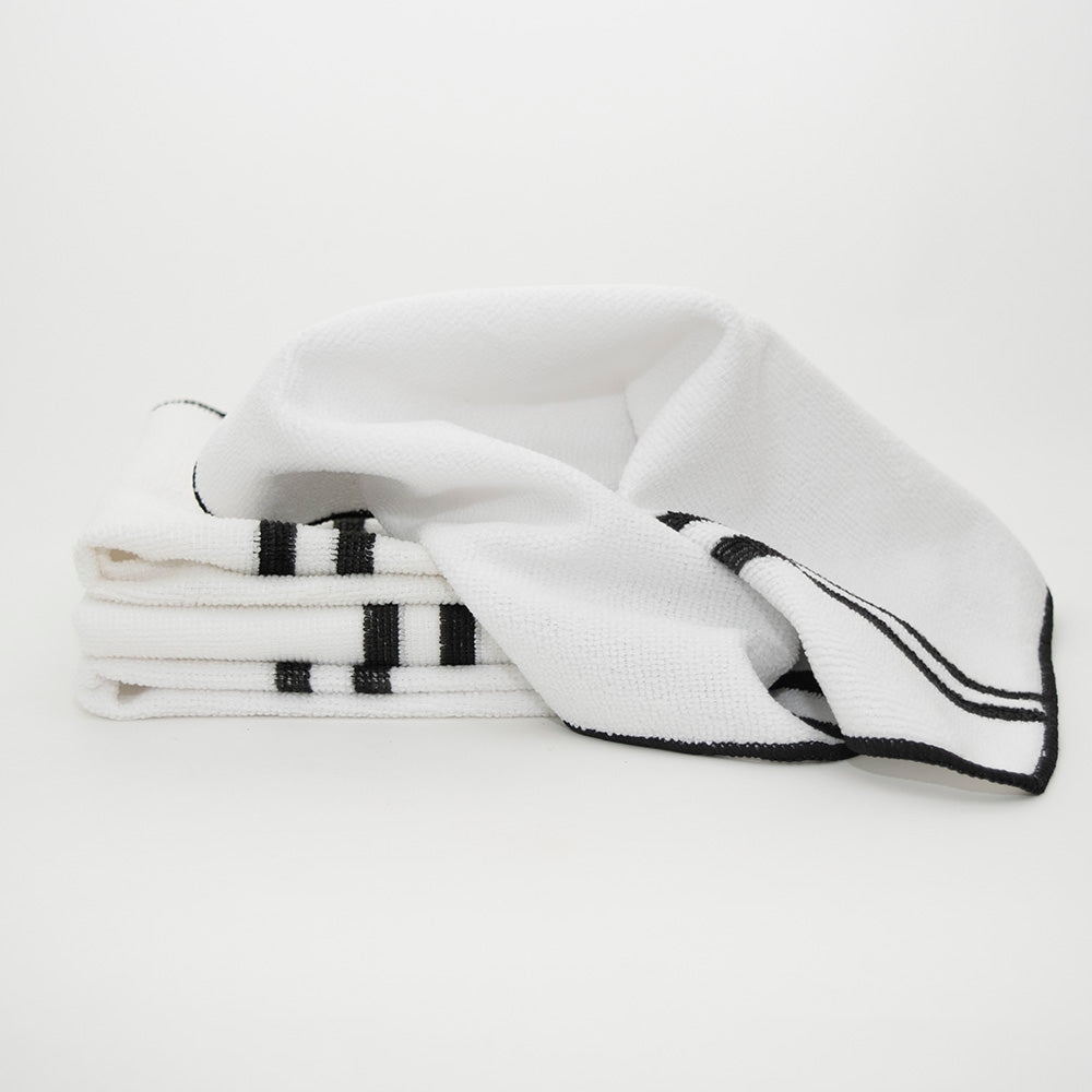 Three Tactfiber Cleaning Cloths by Calderon Textiles, white with black stripes, are neatly folded on a plain white background. One reusable towel is partially unfolded and draped over the others.