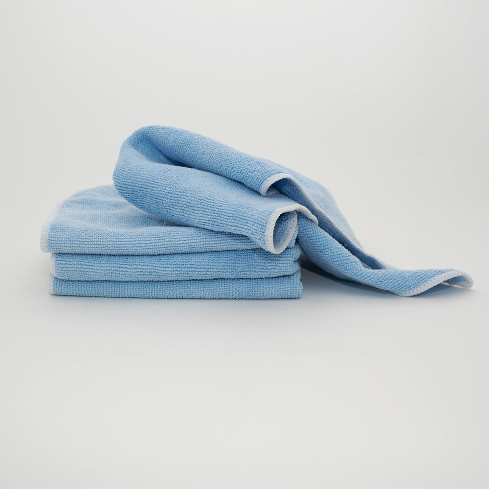 Three light blue Calderon Textiles Microfiber Cleaning Cloths are stacked neatly, with one partially unfolded and draped over the top against a plain white background—ideal for reducing laundering costs.