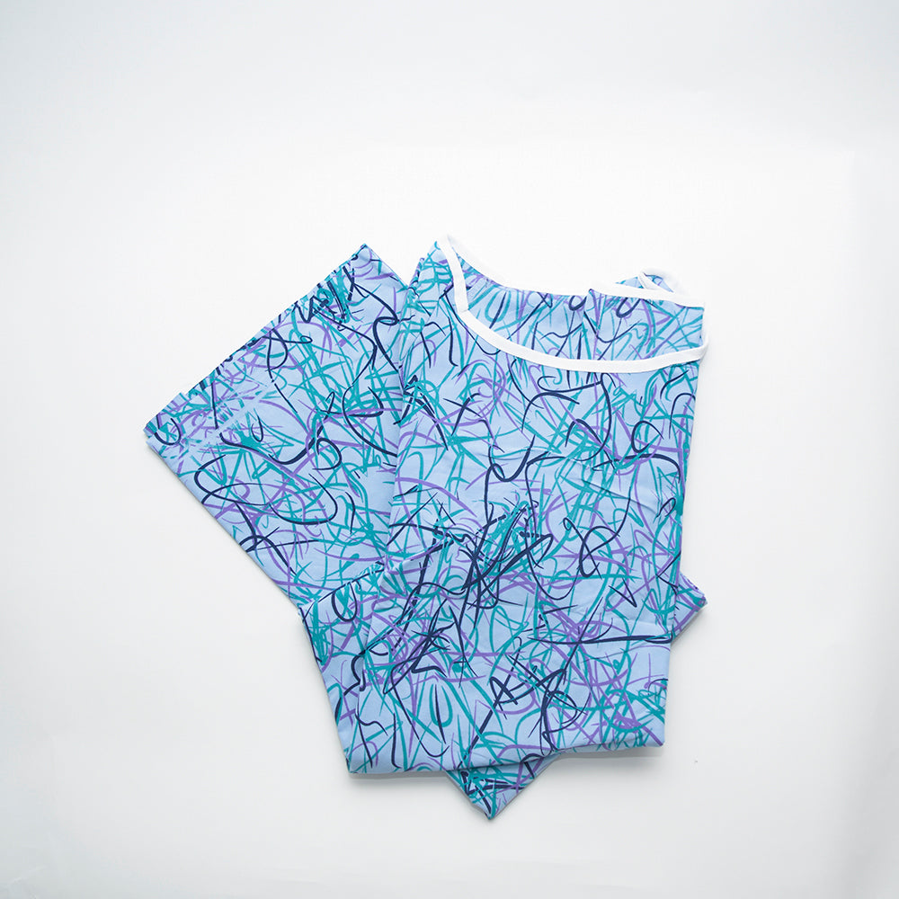 A folded 100% MJS Poly Patient Gown by Calderon Textiles, featuring a blue base with teal and purple abstract squiggle patterns, displayed on white. Enjoy long-lasting vibrancy thanks to Calderon Color Lock technology.
