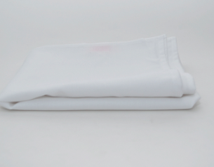 The Prisma Table Cloth Round by Calderon Textiles is neatly folded on a plain white surface, highlighting its impressive durability in a minimal setting.