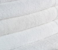 Four neatly stacked KSE Wash Cloths, made from soft 16 single ring spun cotton towels, feature a plush texture and smooth, clean surfaces.