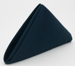 The Prisma Napkin by Calderon Textiles, dyed with Color Lock technology for lasting vibrancy, is dark blue and folded into a neat, upright triangular shape against a plain white background.