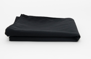 The Prisma Table Cloth Round by Calderon Textiles, a durable and colorfast plain black fabric, is neatly folded and displayed on a white background.