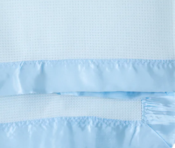 Close-up of the KSE Baby Thermal Blanket in light blue, featuring a waffle texture and shiny satin trim along the edge.
