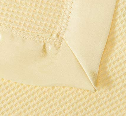 Close-up of the KSE Baby Thermal Blanket in pale yellow, featuring waffle-textured cotton flannel with a smooth satin trim and a neatly stitched folded corner.