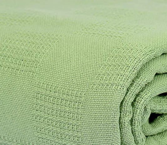 A close-up of the KSE EverLast Spread Blanket in light green polyester, featuring a subtle checkered texture—ideal for hotel use or bulk orders.