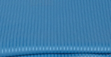 A close-up of KSE Ribcord Bedspread fabric, featuring folded blue material with subtle stripes and fine vertical lines—a smooth, fire-retardant polyester ideal for wholesale bedding needs.