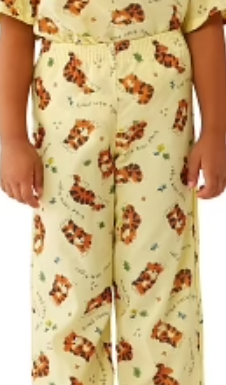 A child wears KSEs Knitted Pediatric PJ Pants - Everlast in yellow, featuring playful tiger faces and small green plants, standing with arms relaxed at their sides.