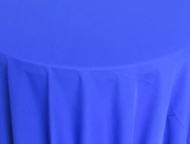 A round table is dressed with a Ganesh Mills Tablecloth - Oxford Blend Satin Band Table Linen in bright blue, gently draping down the sides.