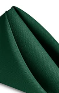 A close-up of a neatly folded Ganesh Mills MagicSpun napkin, made from dark green textured polyester, set against a white background.
