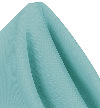 A close-up of a light blue Ganesh Mills MagicSpun napkin, made from textured polyester and neatly folded with soft, overlapping creases.