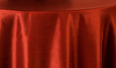 A close-up of the Ganesh Mills Oxford Round Table Linen - Multicolor, draped smoothly over a round surface, reveals its luxurious sheen and soft vertical folds for an elegant, polished look.