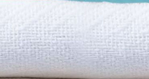 A close-up of Ganesh Mills’ Oxford Herringbone Blankets in white/beige, featuring a textured pattern on a light surface with a blue background—highlighting the comfort and quality of premium cotton hotel blankets.