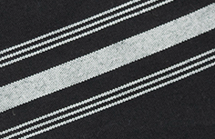 Close-up of the Prisma Napkin, Inverse Stripe by Calderon Textiles—durable black fabric with diagonal white and light gray stripes of varying thicknesses, designed for lasting colorfastness.