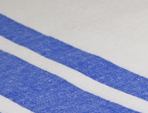 Close-up of Calderon Textiles Bath Blanket Bleached fabric, featuring three parallel blue stripes on a white background with a textured, slightly rough surface—indicative of high-quality cotton blankets.