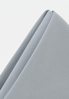 The Prisma Napkin by Calderon Textiles is shown neatly folded with clean edges on a white background, highlighting its light gray color, durability, and stain resistance.