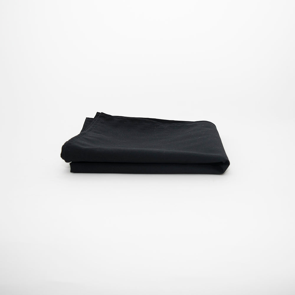 The Prisma Table Cloth by Calderon Textiles, folded neatly on a white surface, highlights its black color, durability, and colorfastness against a minimal background.