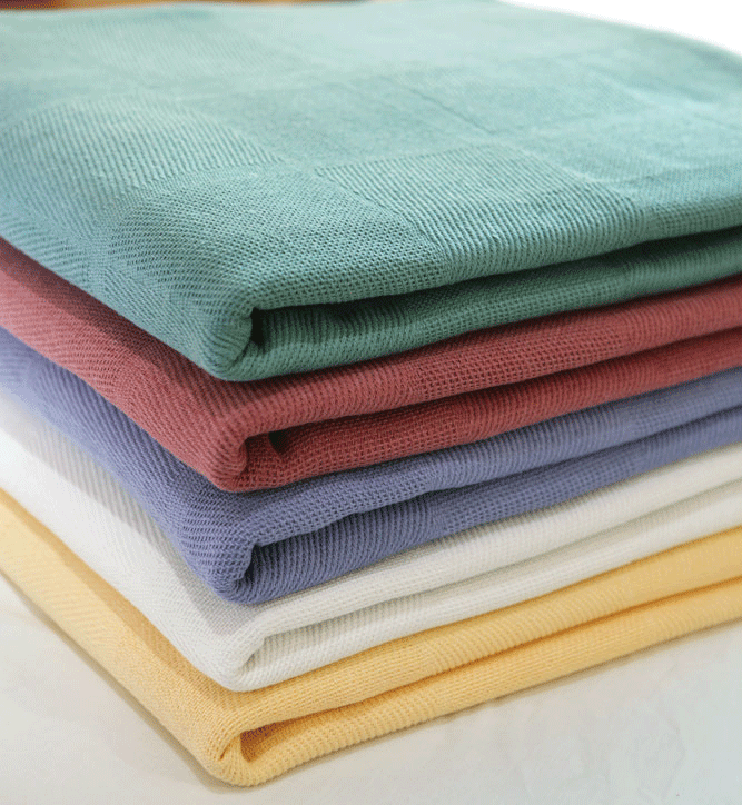 A neatly folded stack of Intralin Lancaster Blended Snag-Free Blankets & Bed Spreads in green, pink, blue, white, light yellow, and beige is arranged horizontally on a light surface.