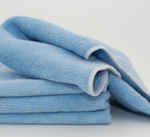 A stack of neatly folded Calderon Textiles Microfiber Cleaning Cloths in light blue on a plain background—designed for reduced laundering costs and effective cleaning.