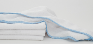 A stack of Calderon Textiles Microfiber Cleaning Cloths with light blue trim, neatly folded on a white surface and one draped casually on top, ideal for reducing laundering costs.