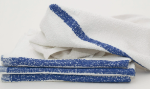 A stack of white Calderon Textiles Meridian Mop bar towels with a blue edge stripe is neatly folded on a white surface, with one economical towel unfolded and draped on top.