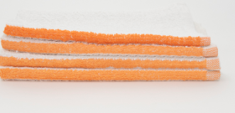 Four Bar Mop Dura towels by Calderon Textiles, made of white cotton terry with orange edges, stacked horizontally against a plain white background.