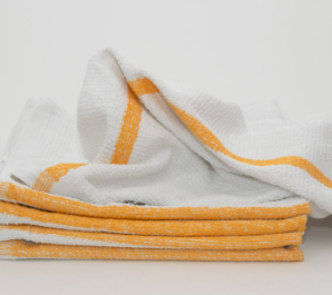 A stack of Calderon Textiles Meridian Mop bar towels, white with orange stripes, is neatly folded with one partially unfolded towel on top, all set against a plain white background.