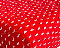 A red tablecloth featuring a repeating pattern of small white crowns inspired by the charming KSE Knitted Bassinet and Crib Sheets.