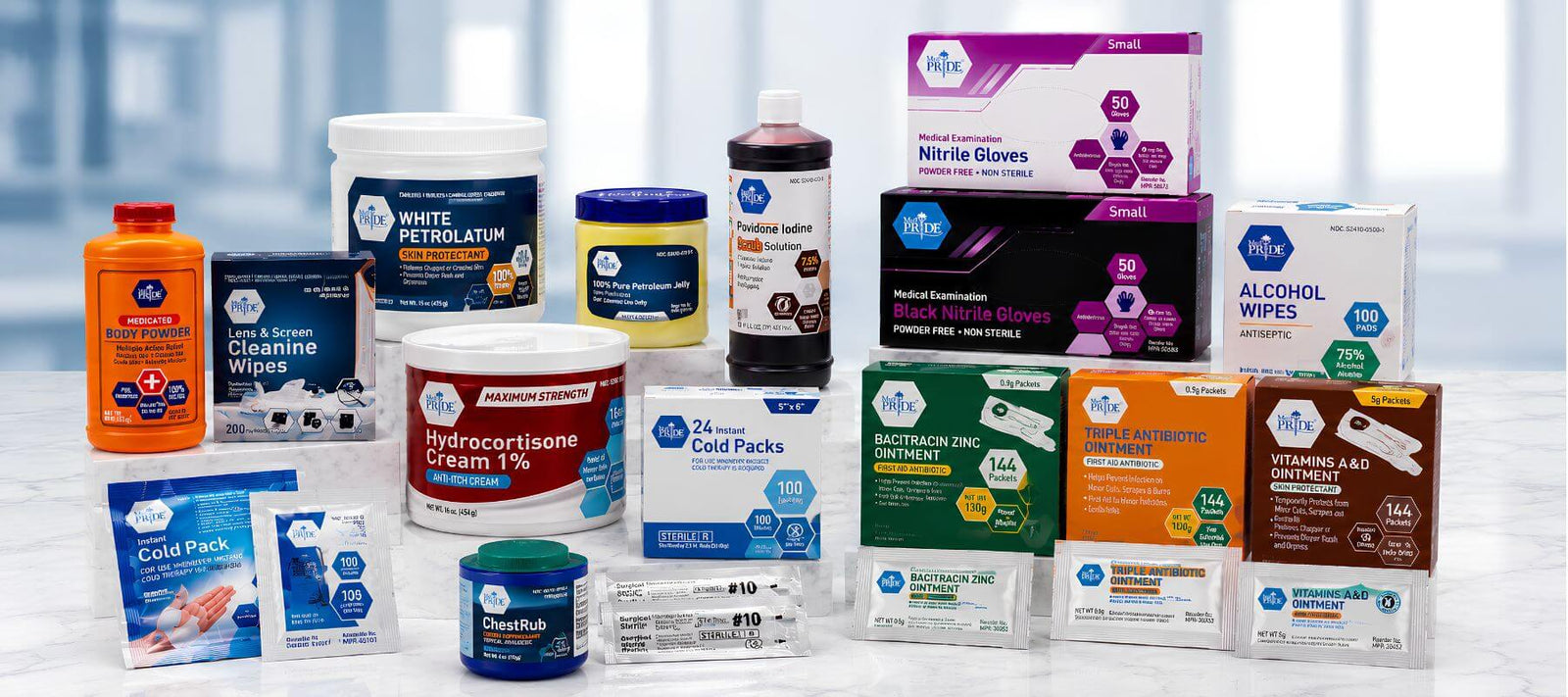 A variety of MedPride medical supplies are displayed on a white surface, including gloves, wipes, creams, cold packs, oral rinse, supplements, and first aid essentials.