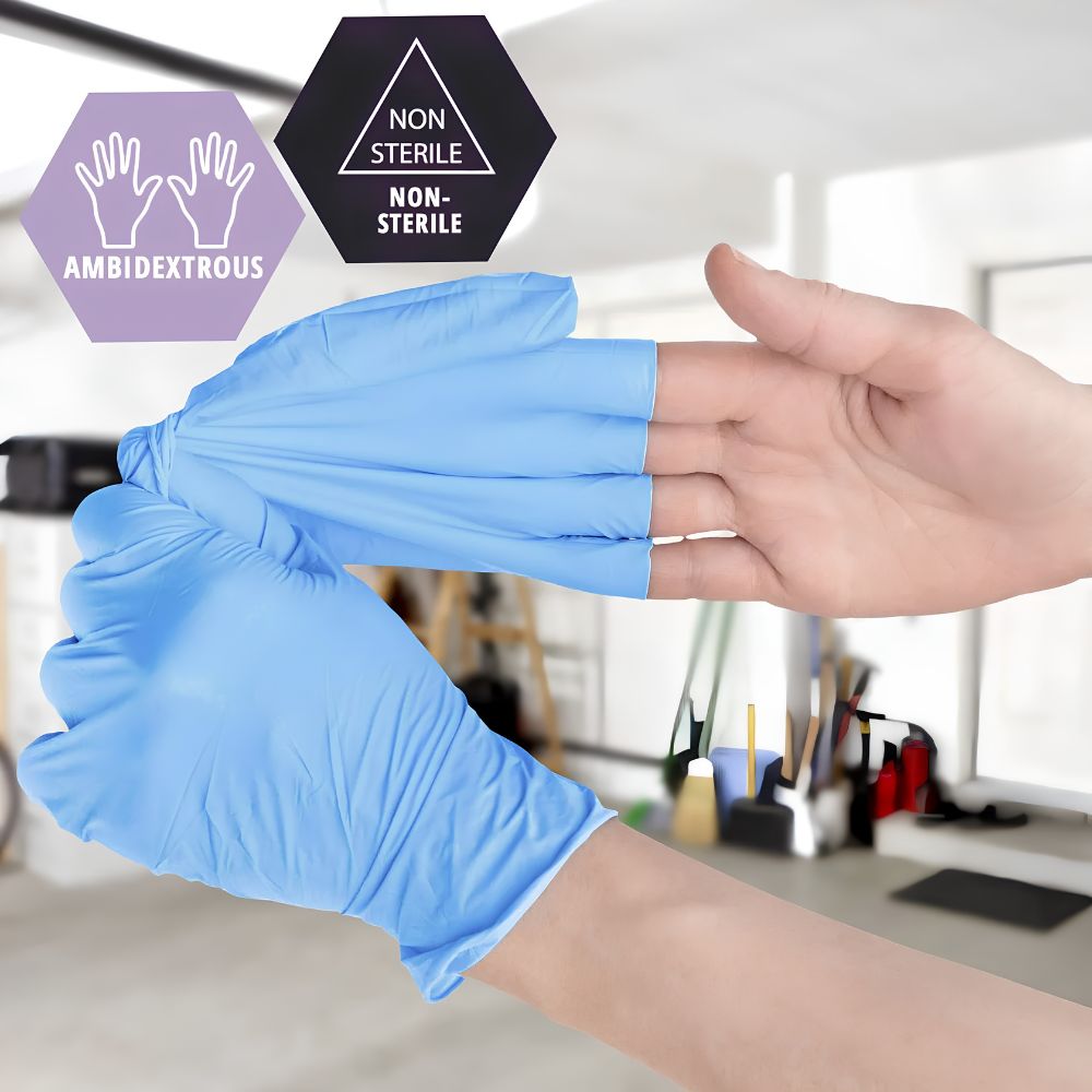A person wears a blue Shield Line MedPride Synthetic Vinyl Exam Glove on one hand and stretches another glove. Icons show Ambidextrous and Non-Sterile. The background displays a blurred indoor workspace. Gloves are 5 mil thick and powder free.